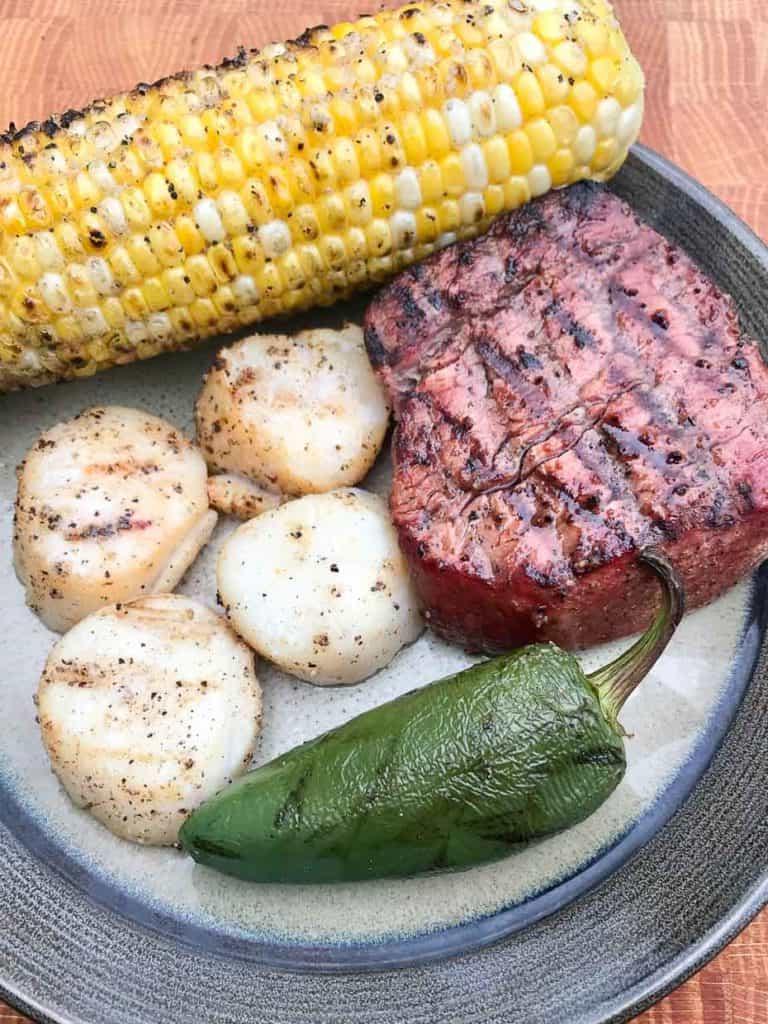 Smoked scallop served on plate with steak jalapeño and corn on the cob