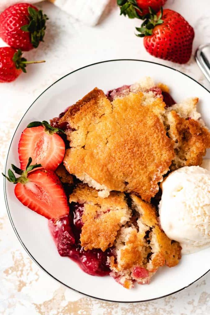 Top down view of scoops of strawberry cobbler on a white dish.