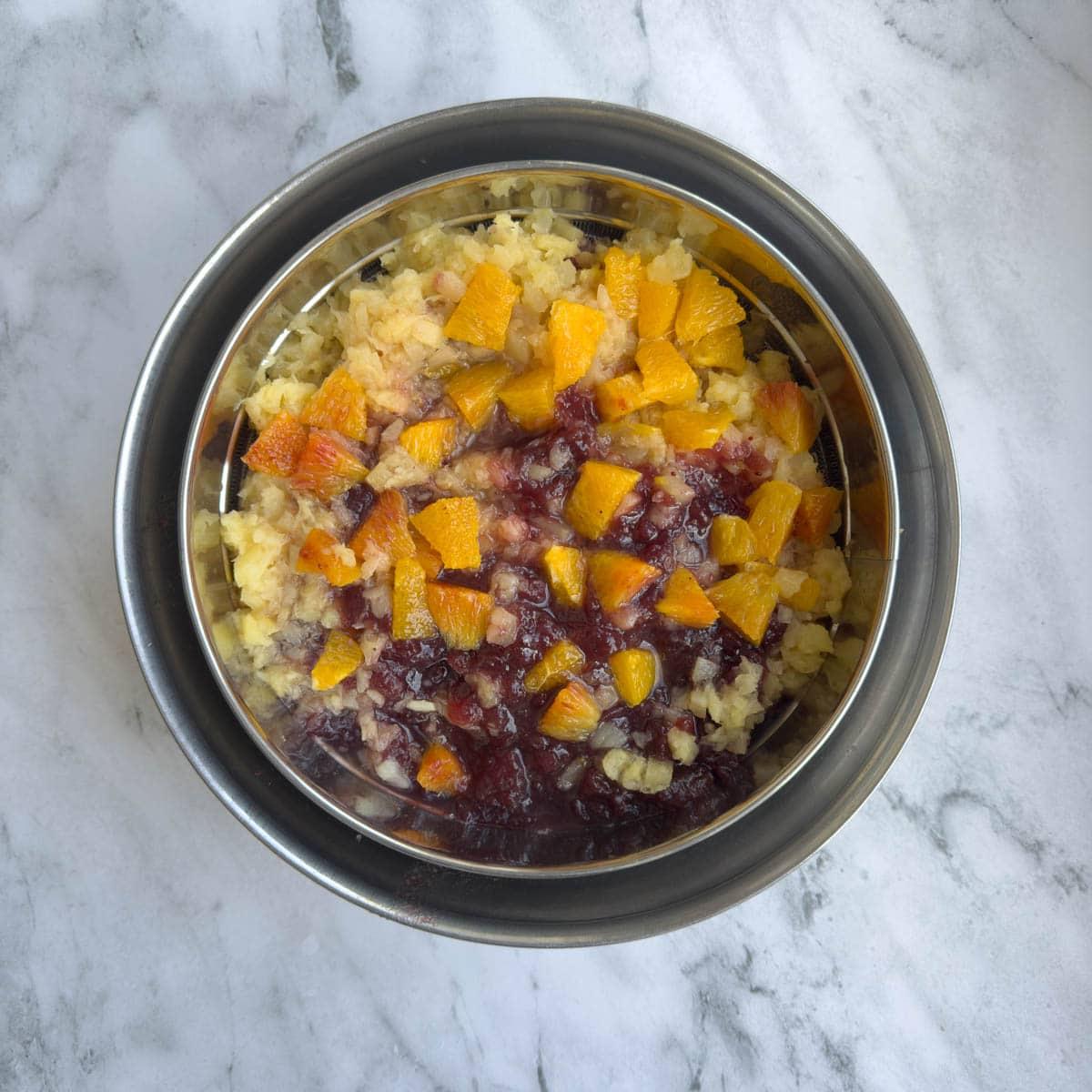 Fruit for a cranberry salad draining in a colander.