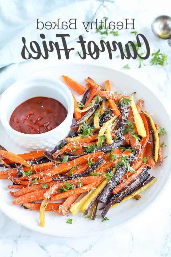 colorful baked carrot fries sprinkled with parsley and cheese on a white plate with ketchup 