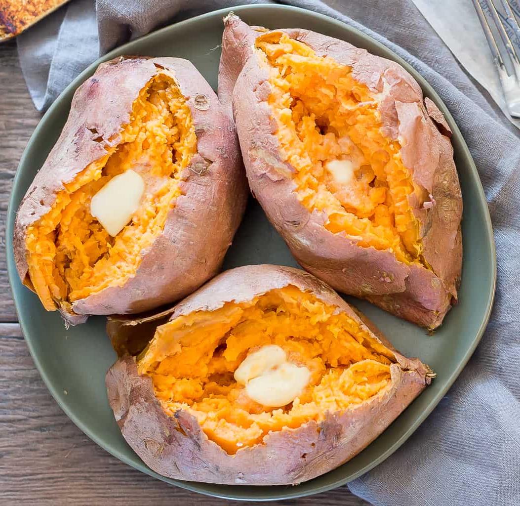 overhead shot of microwaved sweet potatoes with butter on a green earthenware plate