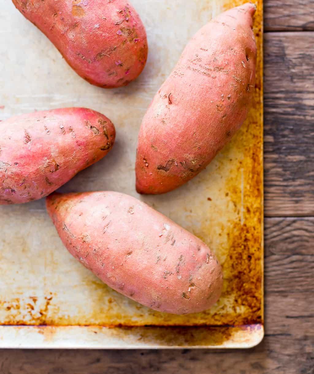 raw sweet potatoes on a sheet pan