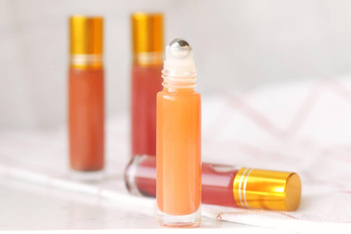 a pink lip gloss in a roller ball bottle with several bottles in the background
