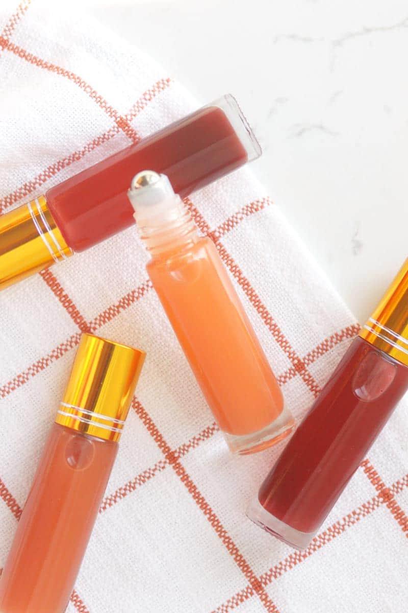 a pink lip gloss in a roller ball bottle with several bottles in the background