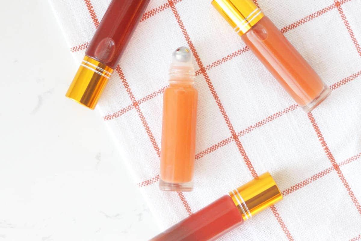 a pink lip gloss in a roller ball bottle with several bottles in the background