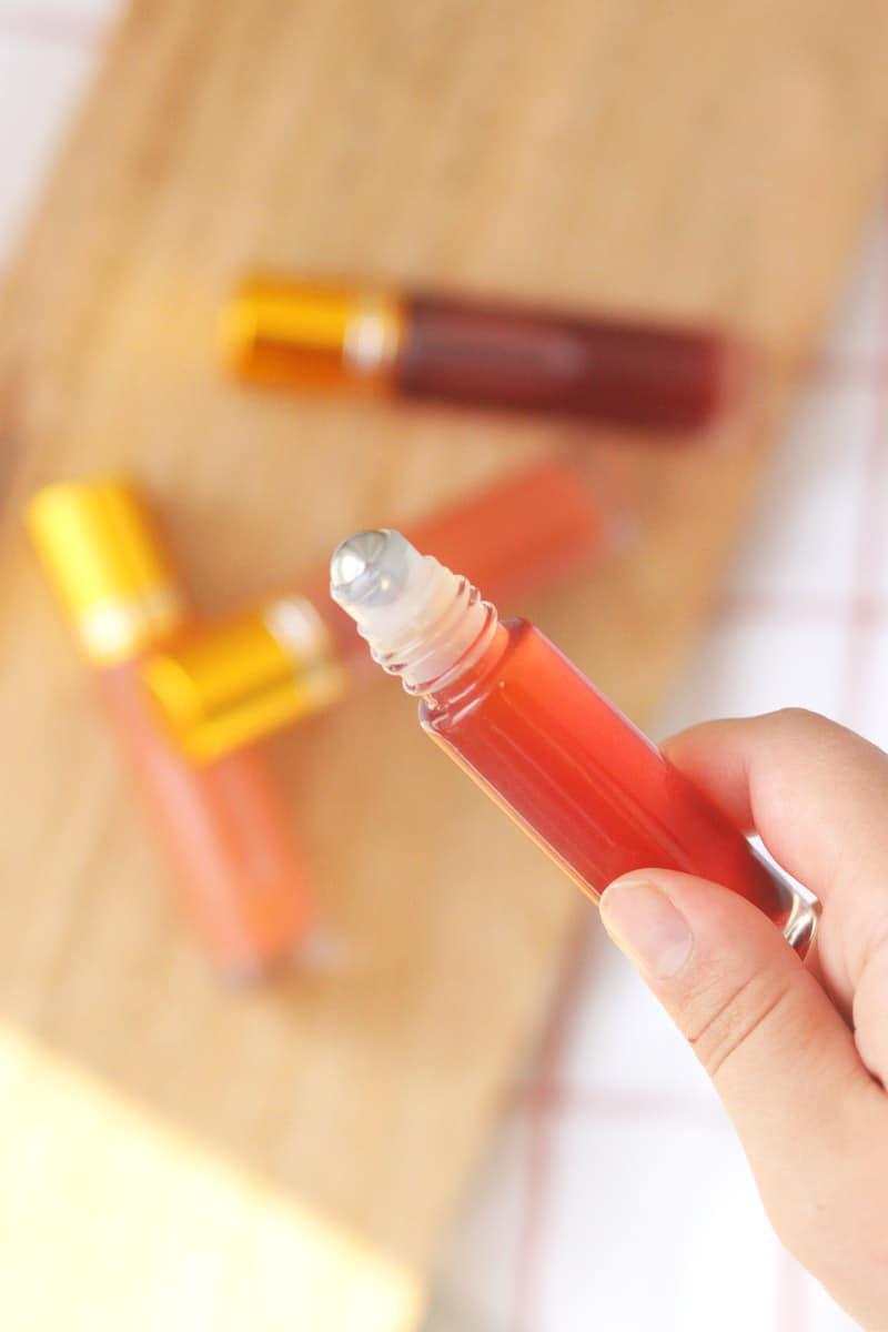 a pink lip gloss in a roller ball bottle with several bottles in the background