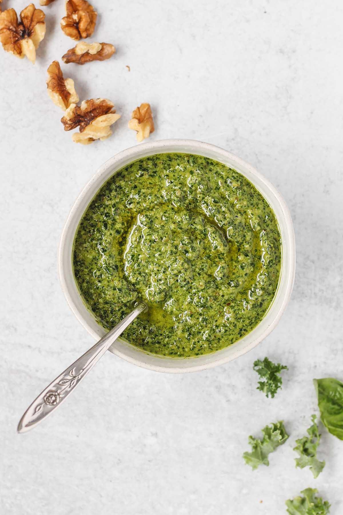 dairy free pesto with a spoon in a small white bowl